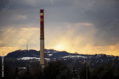 Tall chimney and landscape with sun rays.