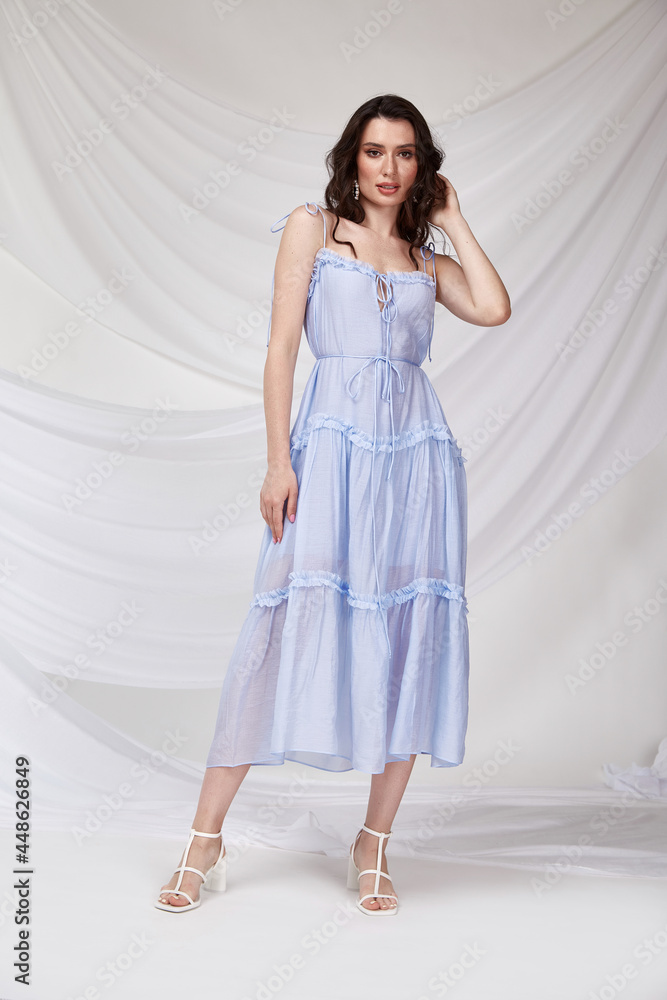 Beautiful sexy woman wear light blue color dress summer collection cotton casual style tanned body brunette hair beautiful face makeup white background studio. Beautiful sexy woman wear light blue color dress summer collection cotton casual style tanned body brunette hair beautiful face makeup white background studio.
