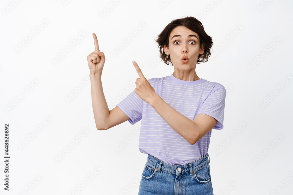 Wow impressive. Excited young woman showing banner, advertisement at upper left corner, pointing at copy space with amazed face, white background Wow impressive. Excited young woman showing banner, advertisement at upper left corner, pointing at copy space with amazed face, white background
