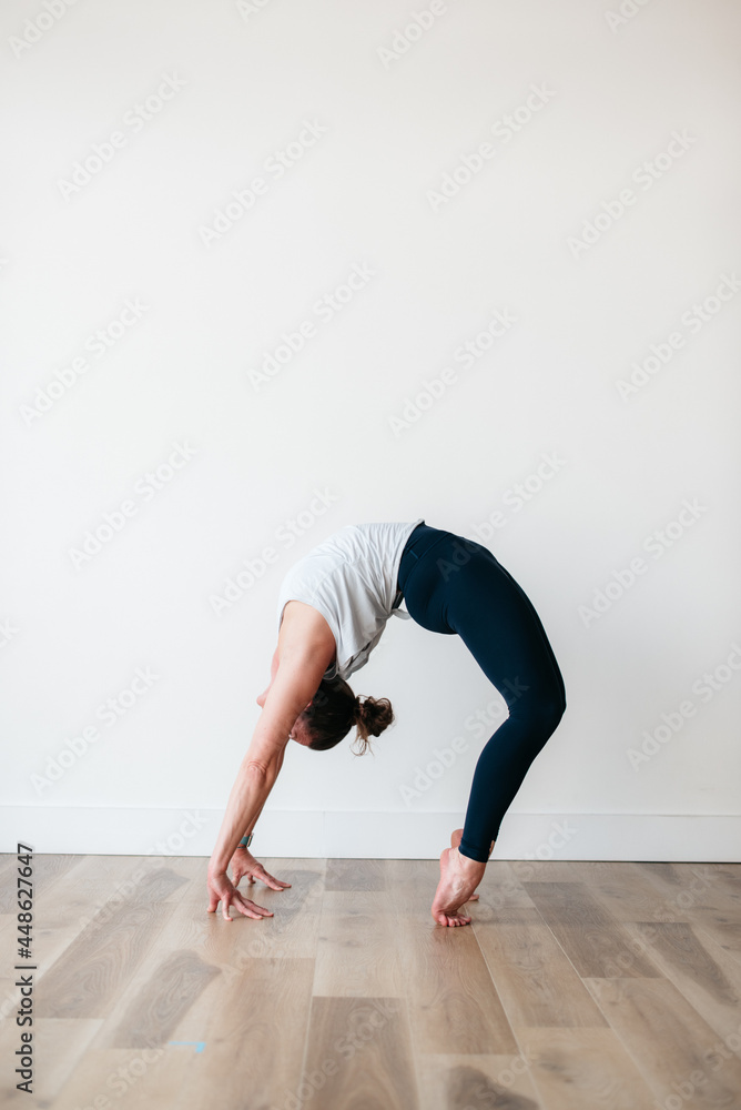 flexible woman holding wheel yoga pose in gym flexible woman holding wheel yoga pose in gym