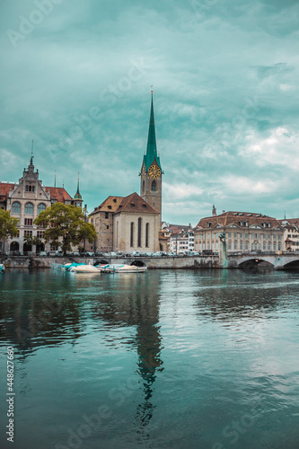 Old town in Zurich city, Switzerland. Panorama of river, bridge, church with a spire and embankment with historic buildings. Pleasure boat. Swiss vacation.