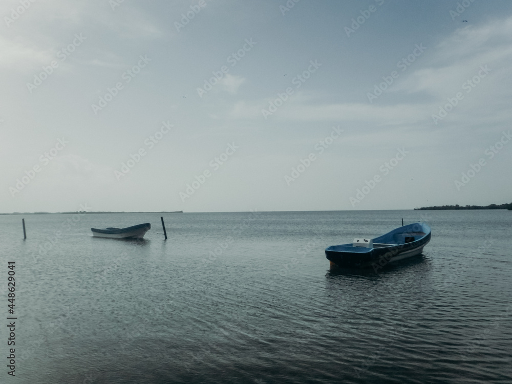 Two boats floating on still blue water with horizon behind Two boats floating on still blue water with horizon behind