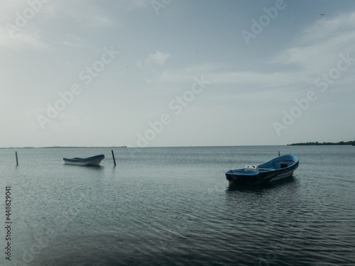 Two boats floating on still blue water with horizon behind photo