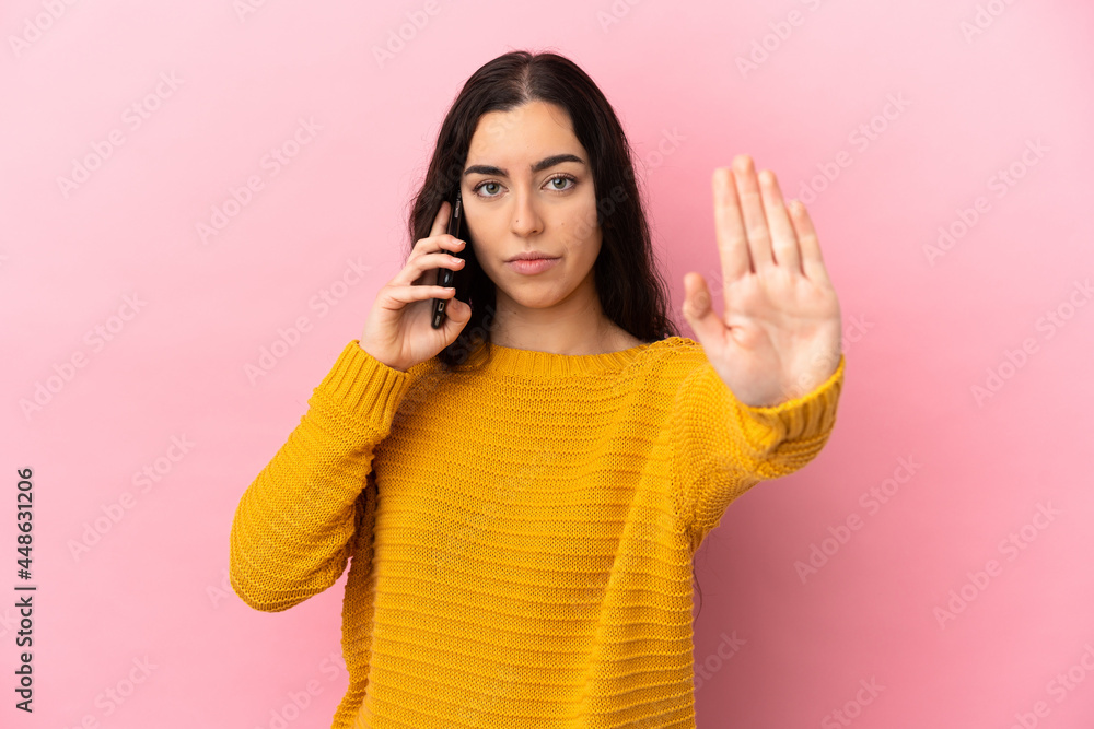Young caucasian woman using mobile phone isolated on pink background making stop gesture Young caucasian woman using mobile phone isolated on pink background making stop gesture