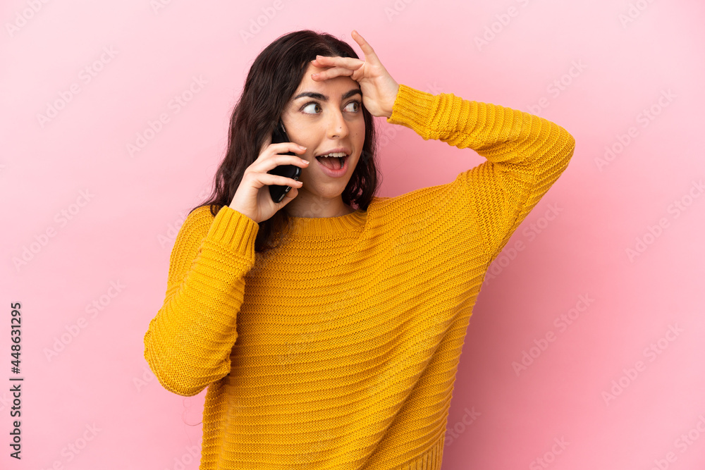 Young caucasian woman using mobile phone isolated on pink background doing surprise gesture while looking to the side Young caucasian woman using mobile phone isolated on pink background doing surprise gesture while looking to the side