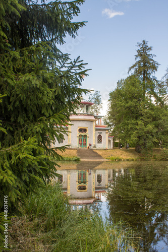 PUSHKIN, Leningrad REGION, RUSSIA-JULY, 21, 2021: a historical pavilion in the Catherine Park on the shore of a pond with a reflection surrounded by green foliage of trees in Tsarskoye Selo