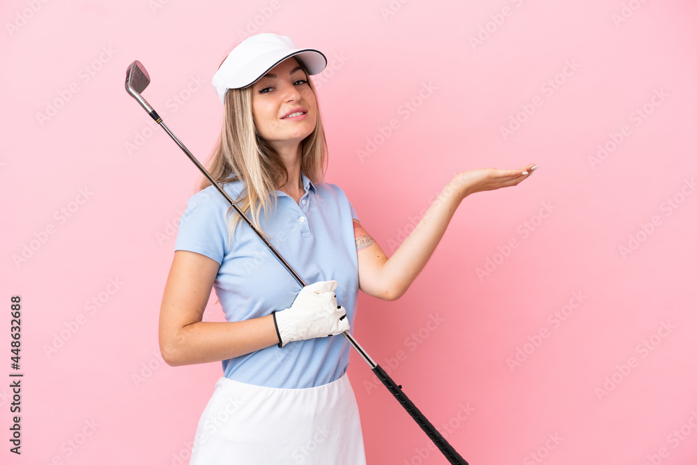 Young golfer player woman isolated on pink background extending hands to the side for inviting to come Young golfer player woman isolated on pink background extending hands to the side for inviting to come