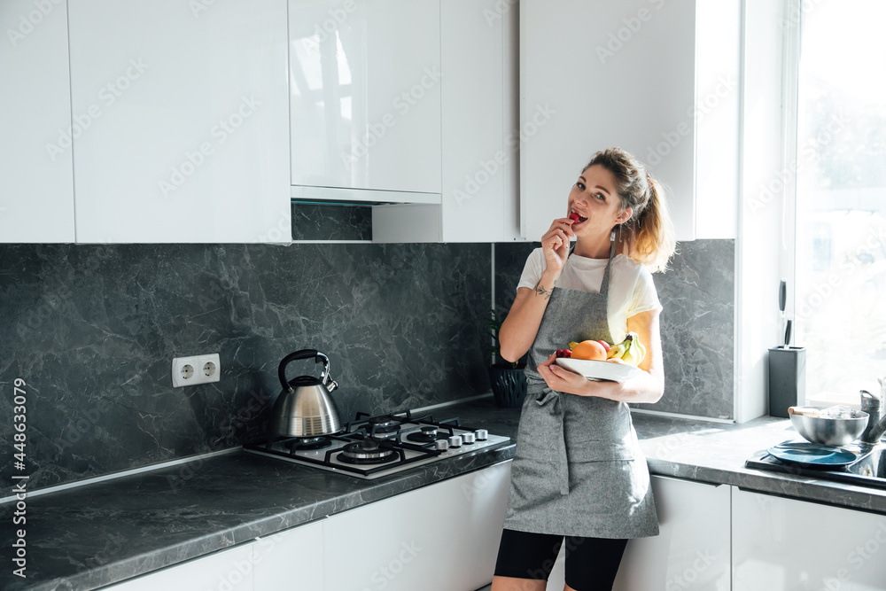 beautiful woman housewife eats sweet fruit in the kitchen beautiful woman housewife eats sweet fruit in the kitchen