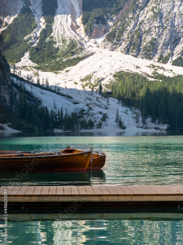 2 wooden rowboats floating on green turquoise lake with mountains in the background, portrait crop