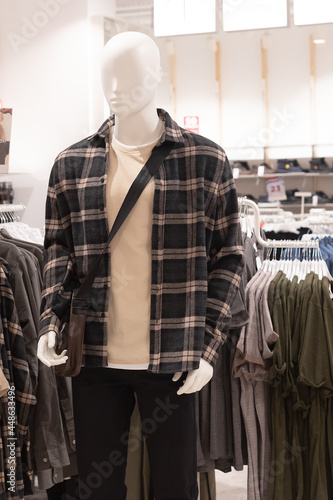 A mannequin in a plaid shirt and black trousers