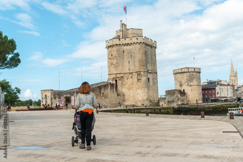 A young mama at Saint Nicolas Tower of La Rochelle and the marina. Coastal town in southwestern France