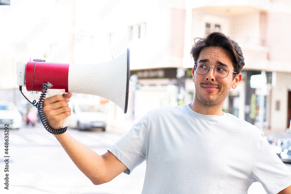 Young caucasian man at outdoors holding a megaphone with stressed expression Young caucasian man at outdoors holding a megaphone with stressed expression