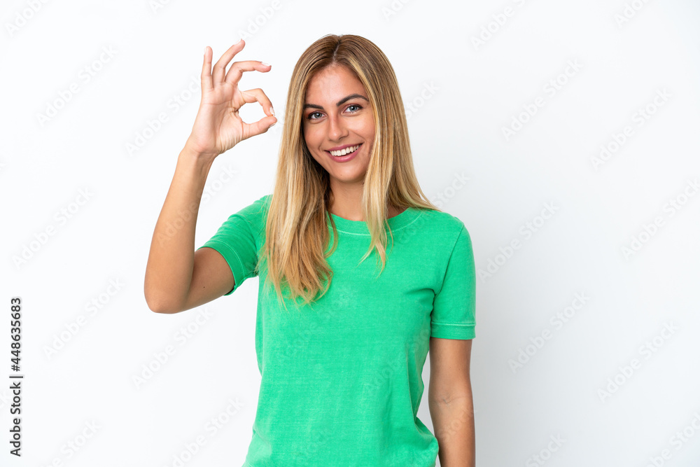 Fototapeta premium Blonde Uruguayan girl isolated on white background showing ok sign with fingers