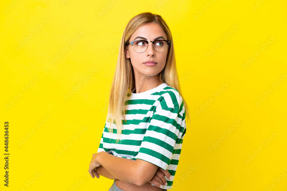 Blonde Uruguayan girl isolated on yellow background keeping the arms crossed