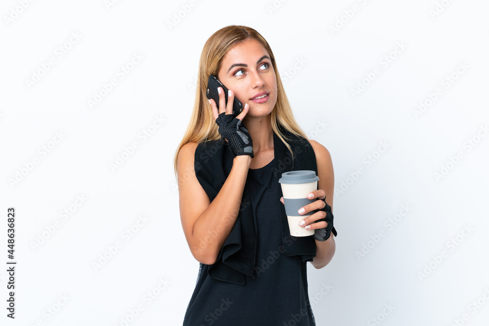 Blonde Uruguayan sport girl isolated on white background holding coffee to take away and a mobile Blonde Uruguayan sport girl isolated on white background holding coffee to take away and a mobile