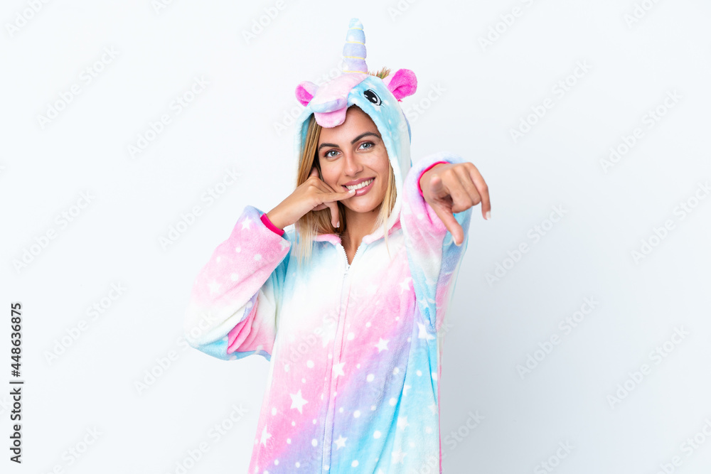 Blonde Uruguayan girl wearing a unicorn pajama isolated on white background making phone gesture and pointing front Blonde Uruguayan girl wearing a unicorn pajama isolated on white background making phone gesture and pointing front