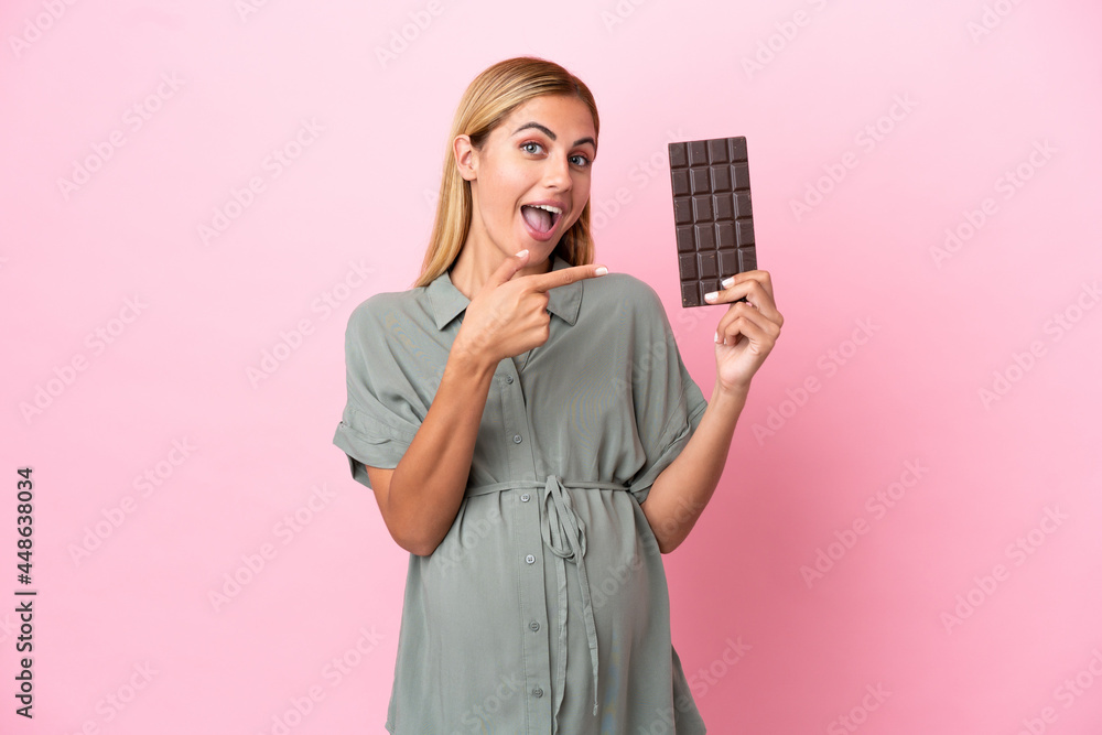 Young Uruguayan woman isolated on blue background pregnant and holding chocolate Young Uruguayan woman isolated on blue background pregnant and holding chocolate