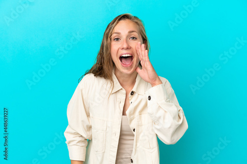 Young caucasian woman isolated on blue background shouting with mouth wide open