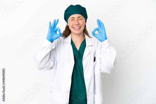 Surgeon caucasian woman in green uniform isolated on white background in zen pose