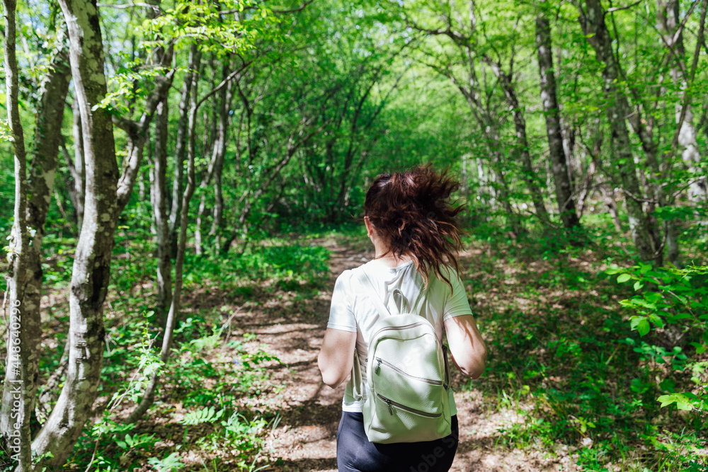 woman walking down the road in a green forest travel hike woman walking down the road in a green forest travel hike