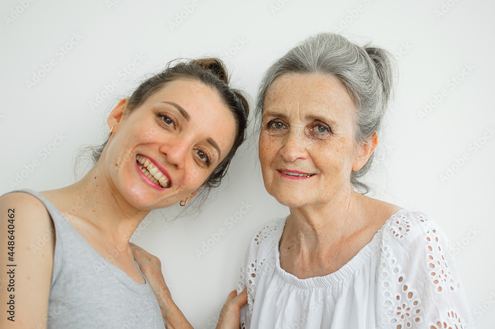 Happy senior mother is hugging her adult daughter, the women are laughing together, sincere family of different age generations having fun on white background, mothers day. Happy senior mother is hugging her adult daughter, the women are laughing together, sincere family of different age generations having fun on white background, mothers day.