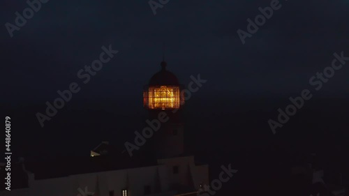 Closeup of shining lighthouse yellow fresnel lens head at dusk in Lagos Algarve, Portugal, aerial drone circling around, evening