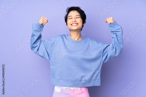 Young Vietnamese woman with short hair over isolated purple background doing strong gesture