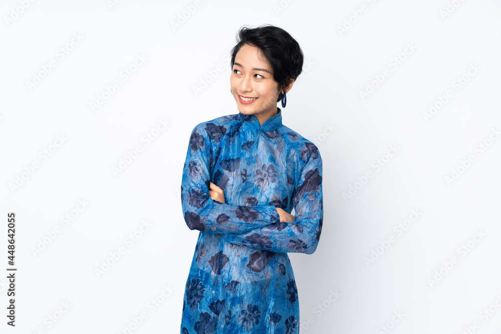 Young Vietnamese woman with short hair wearing a traditional dress over isolated white background looking to the side Young Vietnamese woman with short hair wearing a traditional dress over isolated white background looking to the side