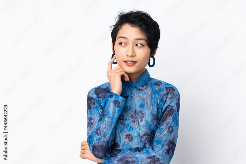 Young Vietnamese woman with short hair wearing a traditional dress over isolated white background Young Vietnamese woman with short hair wearing a traditional dress over isolated white background