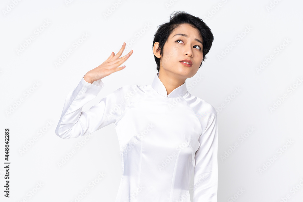 Young Vietnamese woman with short hair wearing a traditional dress over isolated white background with tired and sick expression Young Vietnamese woman with short hair wearing a traditional dress over isolated white background with tired and sick expression