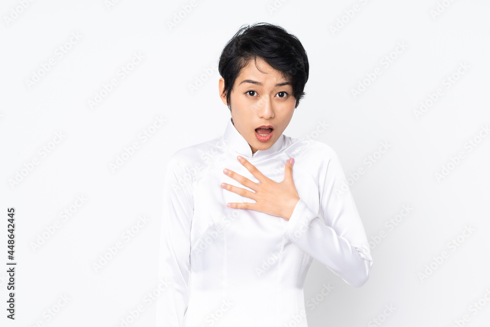 Young Vietnamese woman with short hair wearing a traditional dress over isolated white background surprised and shocked while looking right Young Vietnamese woman with short hair wearing a traditional dress over isolated white background surprised and shocked while looking right