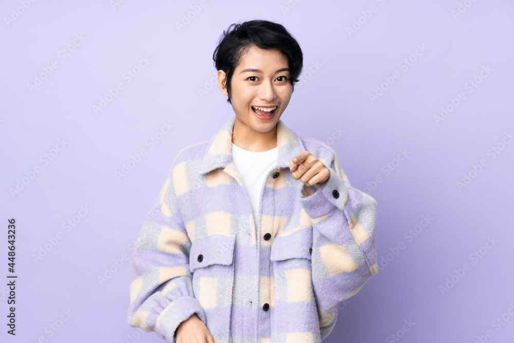 Young Vietnamese woman with short hair over isolated background surprised and pointing front Young Vietnamese woman with short hair over isolated background surprised and pointing front