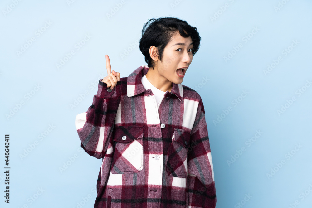 Young Vietnamese woman with short hair over isolated background intending to realizes the solution while lifting a finger up