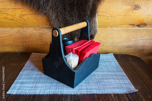 Appliances standing on a rough wooden table in a restaurant, cafe: a salt and pepper shaker and a napkin stand photo