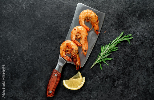 grilled giant prawns on a knife on a stone background