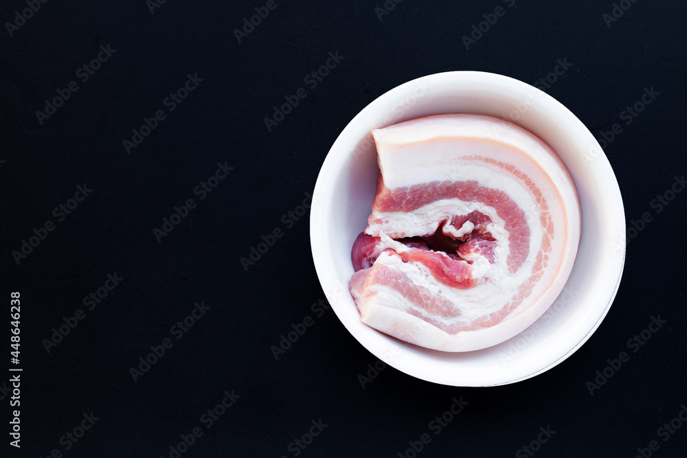 Streaky pork in white bowl on dark background. Streaky pork in white bowl on dark background.