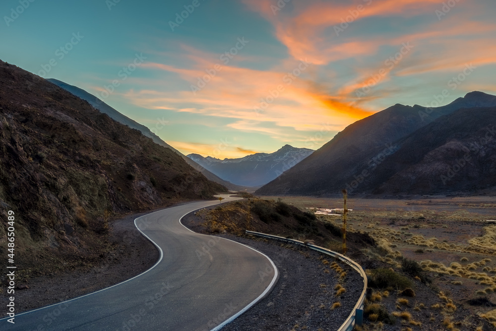 Winding road, between mountains at sunset.