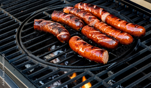 Holiday grilling of sausages in the garden. Baking the best Polish traditional sausage on a grill. Selective focus and horizontal frame.