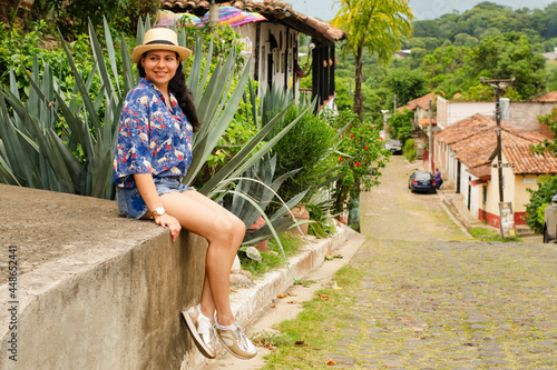 Tourist woman sitting in a rustic colonial village in summer  wearing with colorful cloth and a hat