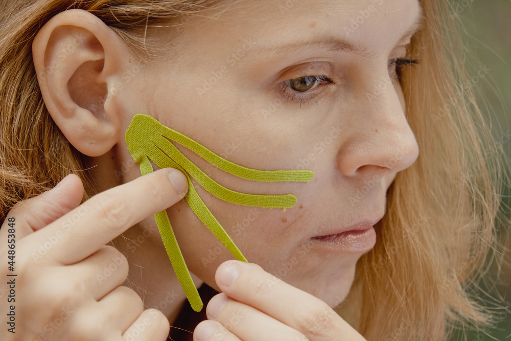 Beautiful Woman With Kinesiology Facelift Tapes. Girl beautician puts