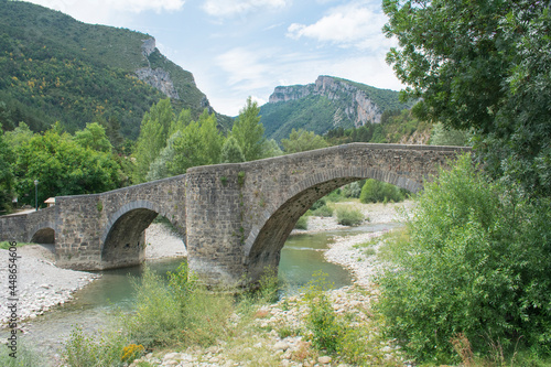 Photograph of a typical landscape of Navarra, Spain with a Roman-style bridge in a natural and mountain environment