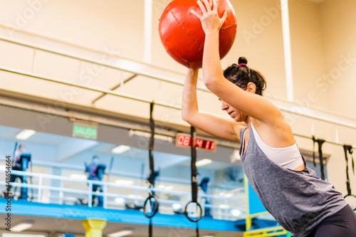 young latin and hispanic woman throwing a medicine ball wearing a top tank.