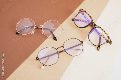 several pairs of eye glasses on a geometric background of different shades of brown