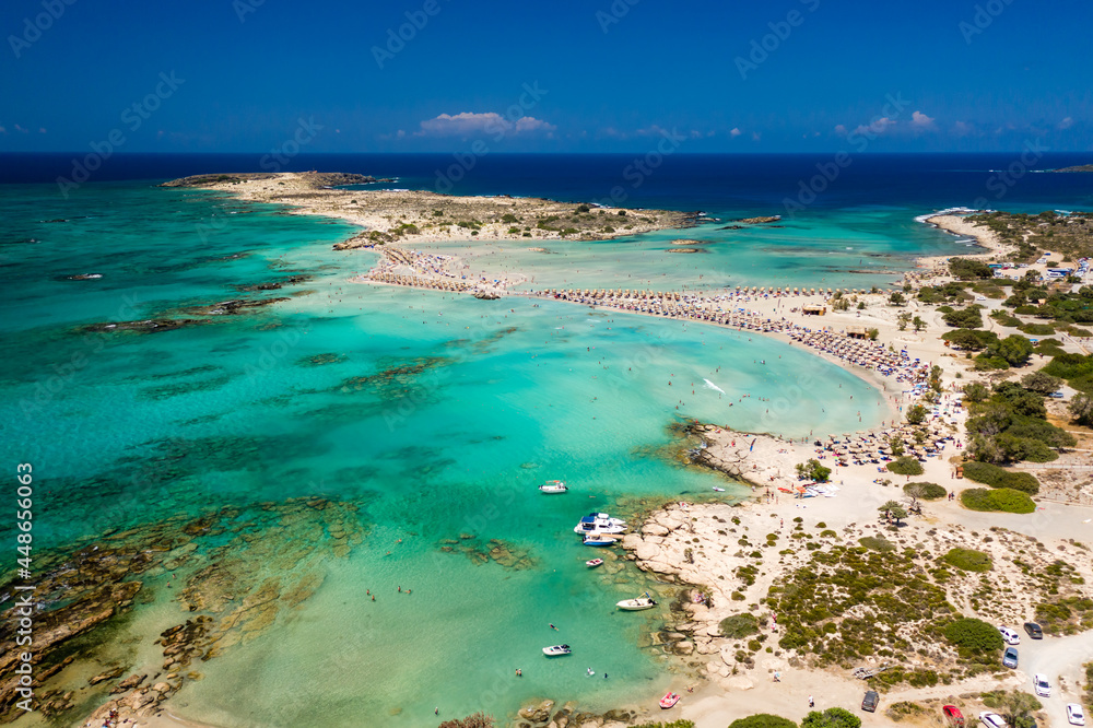 Aerial view of a beautiful but busy sandy beach and shallow lagoons surrounded by clear, blue ocean (Elafonissi, Crete)