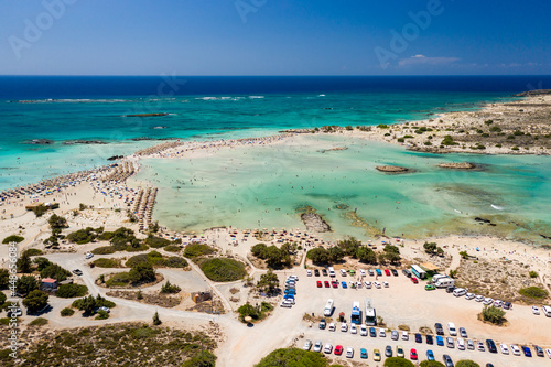 Aerial view of a beautiful but busy sandy beach and shallow lagoons surrounded by clear, blue ocean (Elafonissi, Crete) © whitcomberd