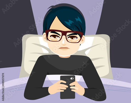 Young Asian man suffering smartphone addiction sleepless on bed at night