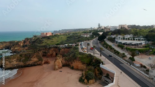 Amazing aerial drone view of Portuguese coastline, drone flying sideway above road in Lagos reveal tourist attraction beaches, Algarve, day