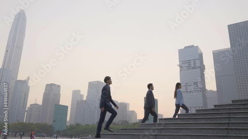 successful asian business people walking ascending steps in downtown financial district of modern city photo