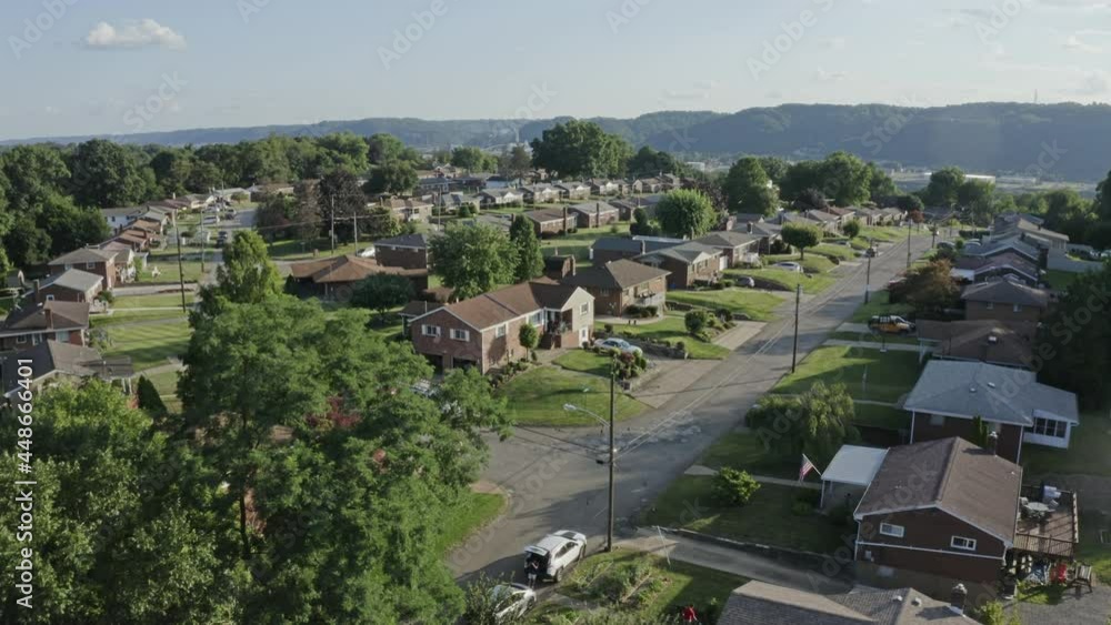 An aerial forward view above a typical Pennsylvania residential neighborhood. Factories along the Ohio River in the distance. Pittsburgh suburbs. An aerial forward view above a typical Pennsylvania residential neighborhood. Factories along the Ohio River in the distance. Pittsburgh suburbs.