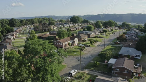 An aerial forward view above a typical Pennsylvania residential neighborhood. Factories along the Ohio River in the distance. Pittsburgh suburbs.  	 photo